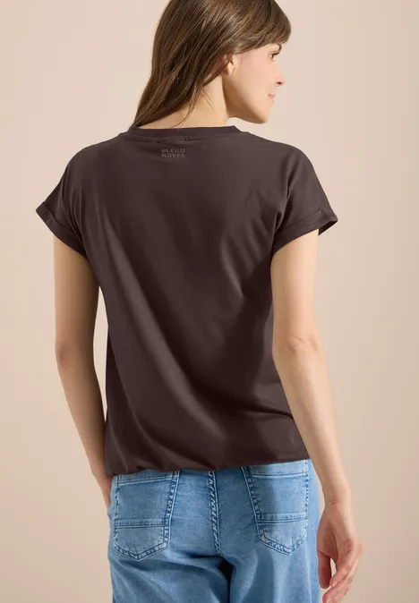 Kurzarm Shirt im Tunika-Look brown cacao Frau von hinten in dunkelgrauem T-Shirt und blauer Jeans vor hellem Hintergrund.
