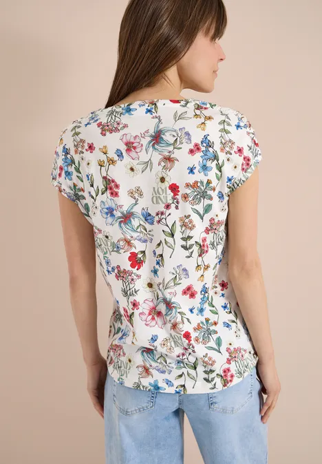 Shirt met bloemenprint light alabaster white Vrouw van achteren in wit shirt met kleurrijke bloemenprint en blauwe jeans.