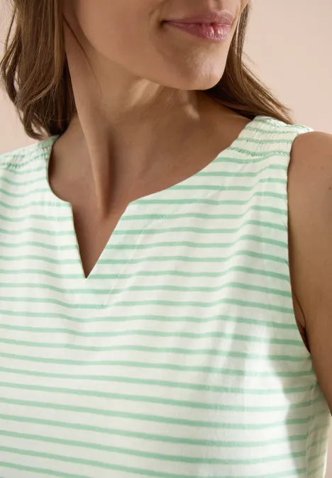 Een vrouw draagt een mouwloos, mintgroen-wit gestreept topje met een subtiele V-hals.