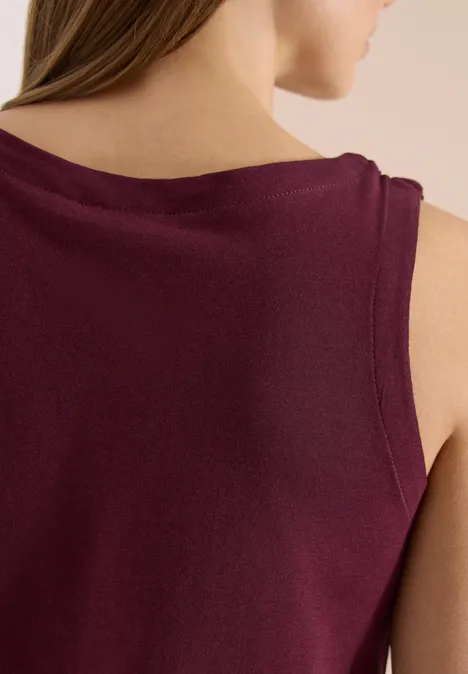 Rückenansicht einer Frau in ärmellosem, bordeauxfarbenem Oberteil