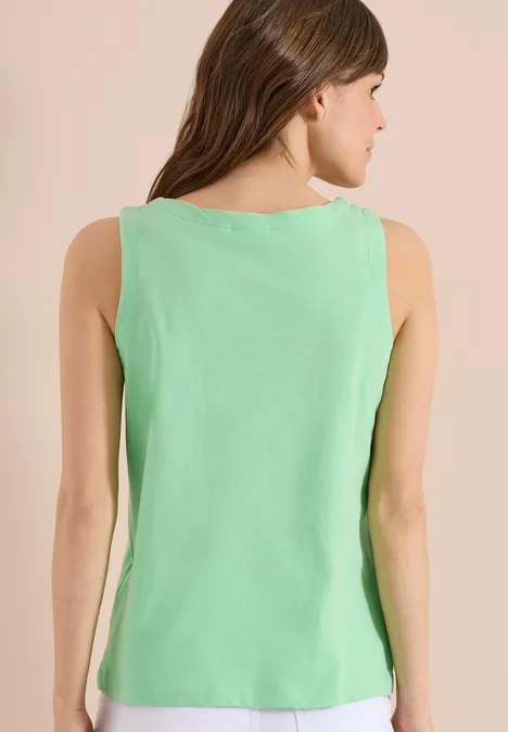 Rückenansicht einer Frau in ärmellosem hellgrünen Top vor beigem Hintergrund