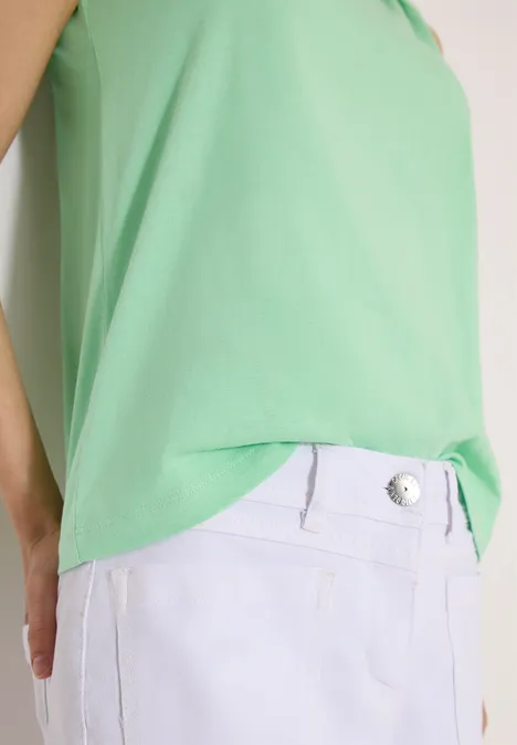 Person trägt ein grünes Top und eine weiße Hose