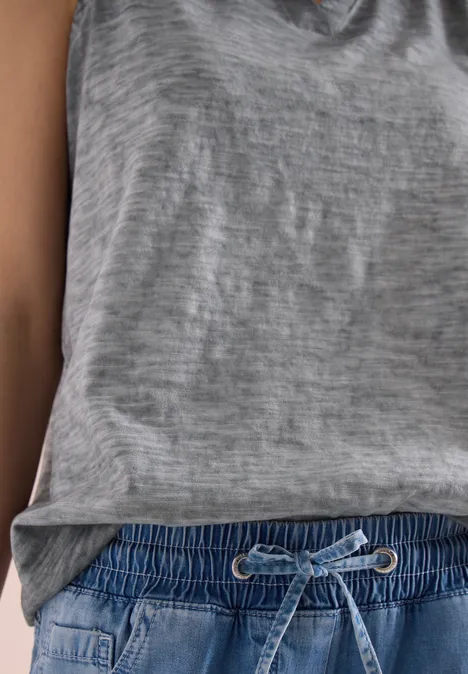 Eine Person trägt ein graues Shirt und eine blaue Jogginghose mit Kordelzug.