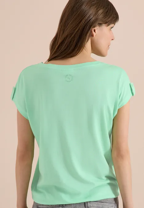 Vrouw van achteren in mintgroen T-shirt met losse korte mouwen, lang bruin haar.