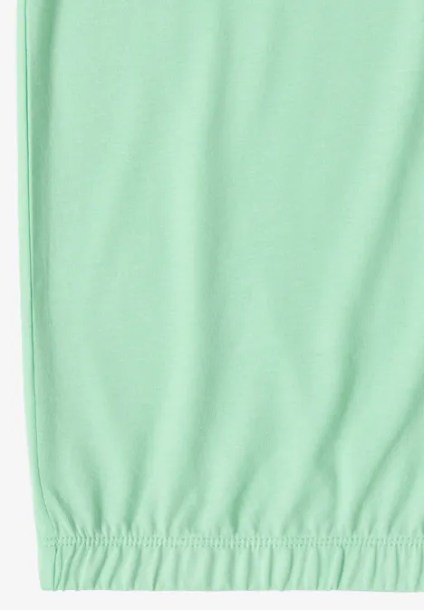 Onderkant van een muntgroen kledingstuk met elastische zoom tegen een witte achtergrond.