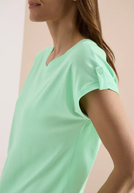 Een vrouw in profiel met een mintgroen t-shirt met korte mouwen.