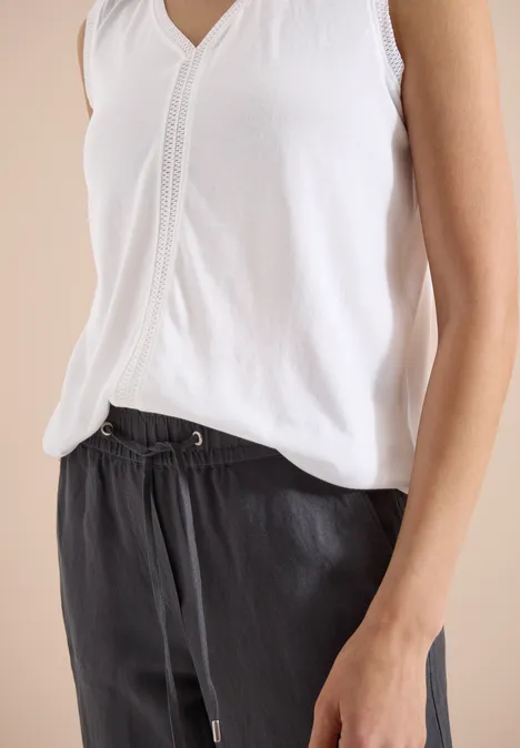 Weißes ärmelloses Top und schwarze Hose mit Tunnelzug, lässiger Stil.