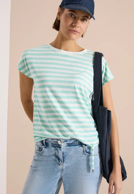 Personne en t-shirt rayé menthe et blanc, jean clair, casquette et sac bleu marine.