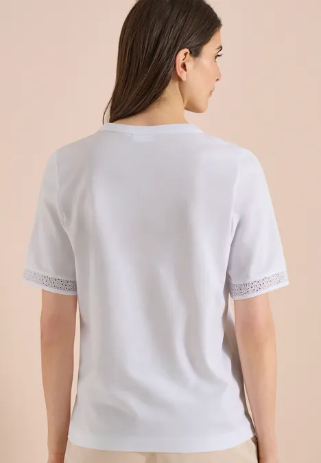 Frau von hinten in weißem Kurzarmshirt mit Spitzenbesatz an den Ärmeln.