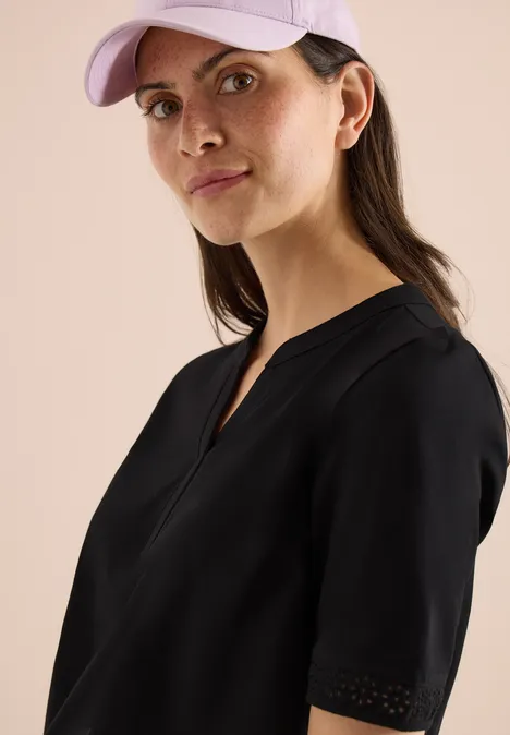 Jonge vrouw in zwarte top en lichtpaarse pet, zijaanzicht