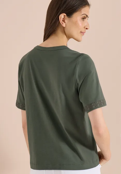 Rugaanzicht: vrouw draagt losse, donkergroene T-shirt met korte mouwen, neutrale achtergrond.