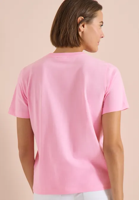 Shirt met ronde hals en frontprint flamingo rose Achteraanzicht van een persoon in een effen roze t-shirt tegen een lichte achtergrond.