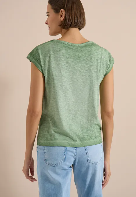 T-shirt en jersey au look garment dye deep matcha green Eine von hinten aufgenommene Frau trägt grünes T-Shirt und blaue Jeans.
