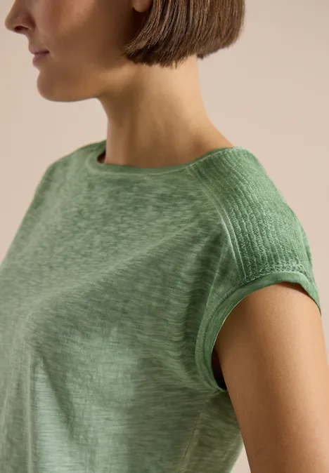 T-shirt en jersey au look garment dye deep matcha green Frau mit kurzem Bob trägt ein hellgrünes, kurzärmeliges Shirt in nahem Porträt.