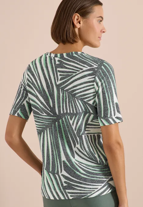 Shirt met boothals en print palm breeze green Vrouw van achteren in een kort mouwig T-shirt met groen-zwart plantenbladmotief.