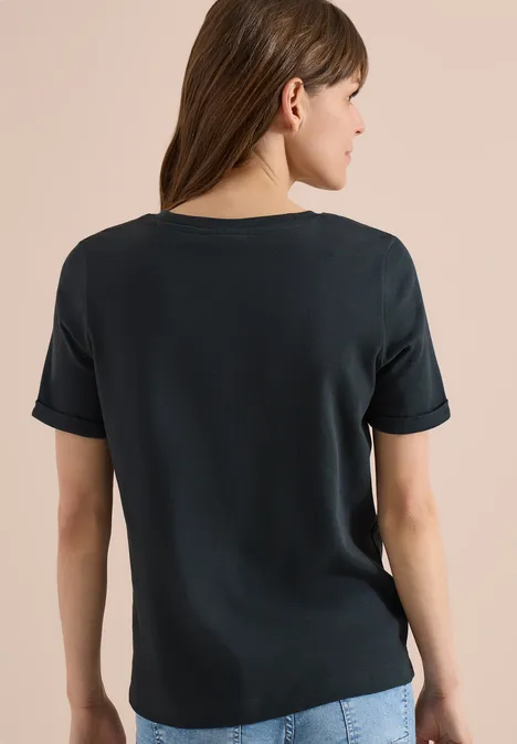 Vrouw van achteren in een eenvoudig zwart t-shirt voor een beige achtergrond