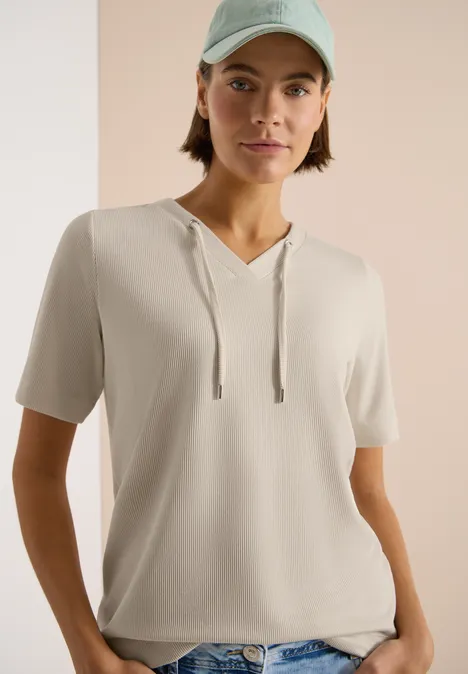 Gestreept shirt pearl beige Persoon draagt lichtbeige korte mouw hoodie-shirt voor neutrale achtergrond.