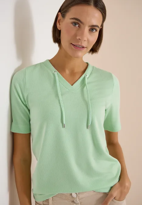 Gestreept shirt juicy lime Vrouw draagt mintgroen kort T-shirt met capuchon en V-hals, staat ontspannen met één hand in de zak.