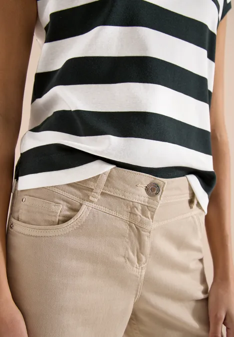 Beige Hose und schwarz-weiß gestreiftes Top an weiblichem Oberkörper