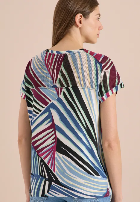 Femme de dos portant un t-shirt multicolore à manches courtes avec motif de rayures abstraites.