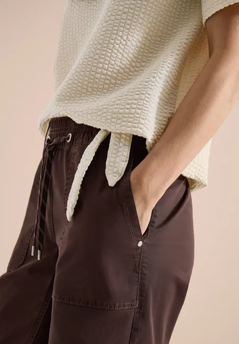 Shirt in seersucker stof pearl beige Damesoutfit met lichtbeige, gestructureerde top en losse donkerbruine broek met zakken