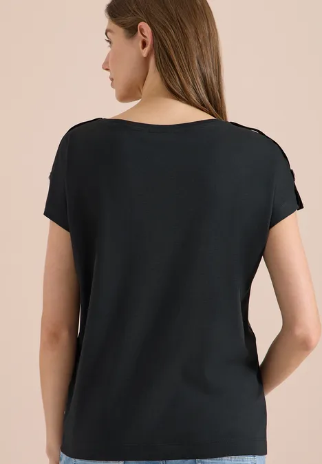 Rückansicht einer Frau in schlichtem, schwarzem T-Shirt vor neutralem Hintergrund.