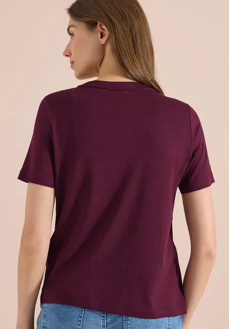 Eine Frau von hinten in lila T-Shirt und Jeans.