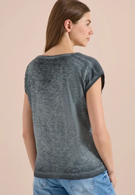 T-Shirt mit Boatneck im Garment-Dye-Look volcanic grey Frau steht von hinten in grauem T-Shirt und Jeans vor hellem, einfarbigem Hintergrund.