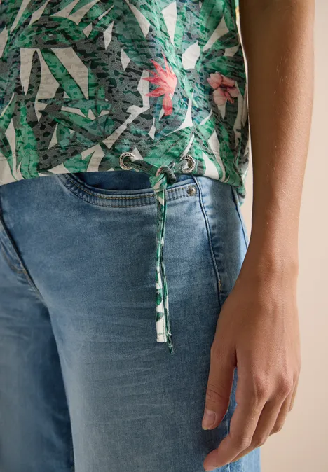 Shirt met burn-out look khaki Persoon draagt blauwe jeans en groene top met print en zijstrikje