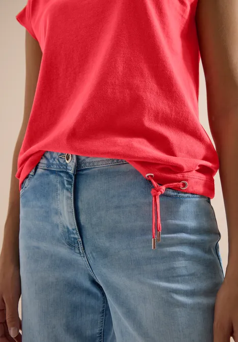Rotes Top und lockere blaue Jeans, seitliche Oberkörperansicht