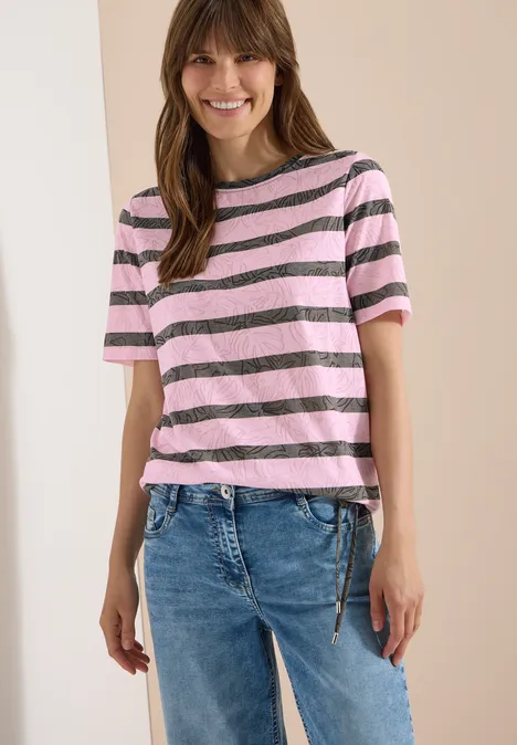 Eine Person trägt ein rosa-grau gestreiftes T-Shirt mit kurzen Ärmeln und blaue Jeans.