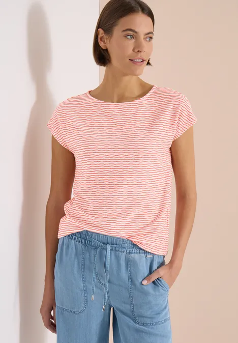 Femme en t-shirt rayé rose et blanc et pantalon jean bleu clair décontracté sur fond clair.