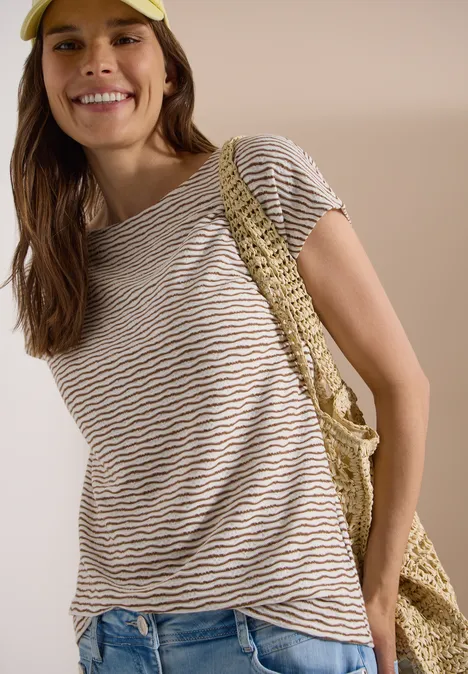 Vrouw in gestreept T-shirt en jeans met gehaakte schoudertas.