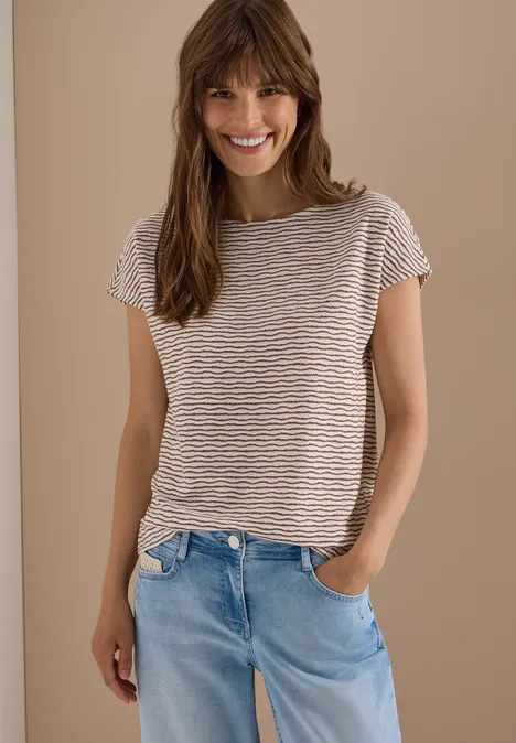 Vrouw in gestreept shirt en lichtblauwe jeans, casual, voor een beige muur