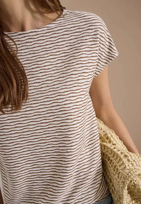 Persoon met wit-bruin gestreept T-shirt, houdt een gevlochten strozak vast.