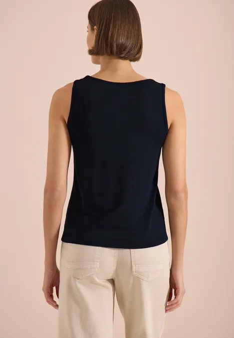 Top avec col en V arrondi et détail tressé universal blue Femme de dos portant un top bleu marine sans manches et un pantalon clair