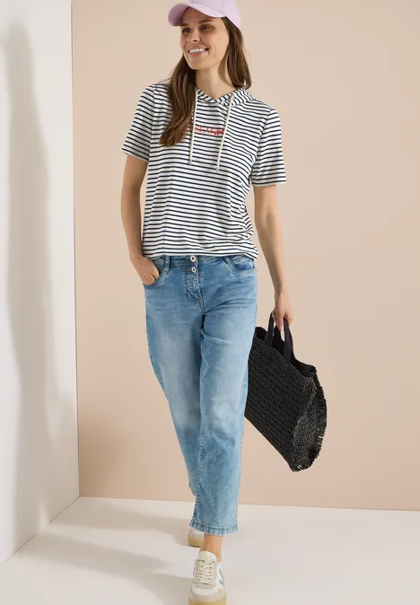 Kurzarm Shirt mit Kapuze und Glitzer vanilla white Frau mit Streifenshirt, blauen Jeans und einer geflochtenen Tasche.