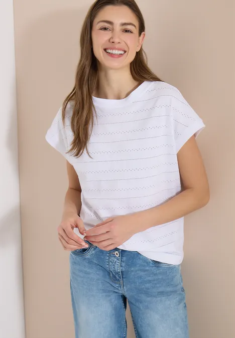 T-shirt structuré avec col bateau White Frau mit weißem T-Shirt und blauen Jeans lehnt an hellem Hintergrund.