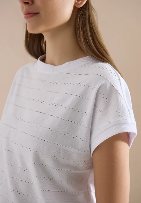 T-shirt structuré avec col bateau White Seitliche Ansicht einer Frau in weißem kurzärmeligem Oberteil mit Lochmuster vor neutralem Hintergrund.