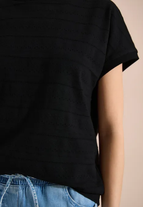 T-shirt structuré avec col bateau Black Person trägt schwarzes T-Shirt mit feinen Streifen und blaue Jeans, Oberkörperansicht ohne Gesicht