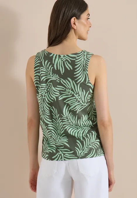 Top met split in de hals en tweekleurig patroon khaki Achteraanzicht van een vrouw in een groen topje met bladprint en witte broek