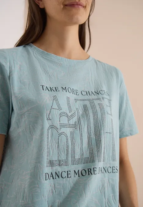 T-Shirt in Ausbrenner-Optik crystal mint Dame in blauem T-Shirt mit 'Take More Chances, Dance More Chances' Schriftzug und Muster