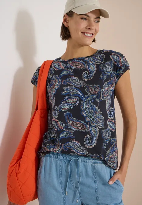Kurzarm Shirt mit Boat Neck und Raffung universal blue Frau mit paisleygemustertem Shirt, Jeans und roter Schultertasche.