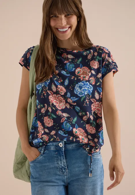 Shirt met korte mouwen, boothals en rimpels urban dark blue Vrouw in jeans draagt een donkerblauw t-shirt met kleurrijke bloemenprint en een groene schoudertas.