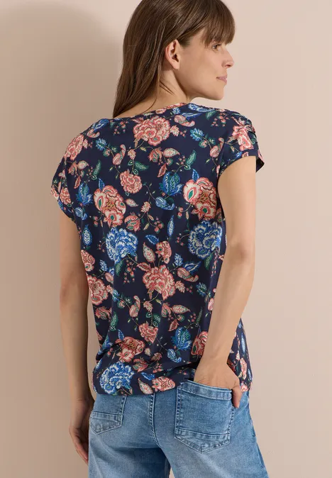 Shirt met korte mouwen, boothals en rimpels urban dark blue Vrouw van achteren in donkerblauw bloemen-T-shirt en spijkerbroek, lichte achtergrond.