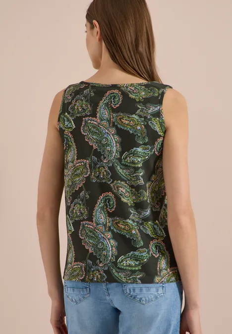 Rückansicht einer Frau mit ärmellosem Top in schwarzem Paisley-Muster und blauen Jeans.