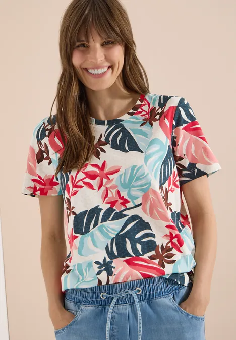 Frau trägt T-Shirt mit tropischem Blumen- und Blattmuster