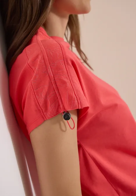 Shirt met rimpels in effen kleur coral Rood T-shirt met een kabel en stekker aan de mouw, zittend persoon in profiel
