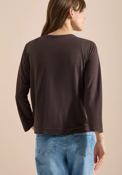 Veste ouverte en couleur unie avec manches 3/4 brown cacao Femme vue de dos portant un haut noir à manches longues et un jean bleu sur fond clair.