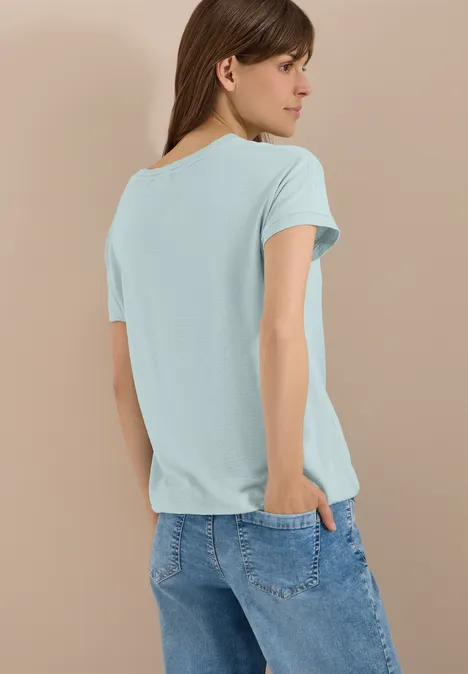 T-Shirt mit Rundhals und Struktur crystal mint Frau von hinten in türkisfarbenem T-Shirt und blauen Jeans vor beigem Hintergrund.